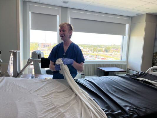 Young man with disabilities putting sheets on a hospital bed