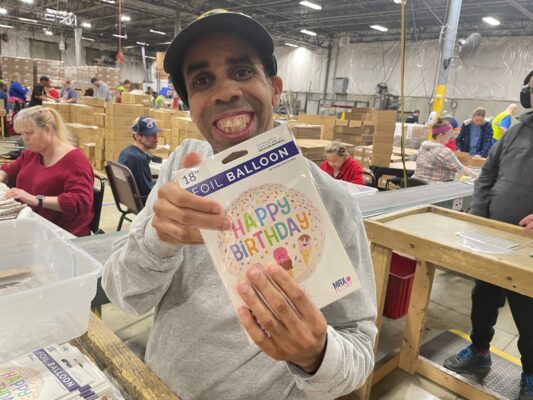 A young man showing a foil balloon he just packaged in his job at BCI