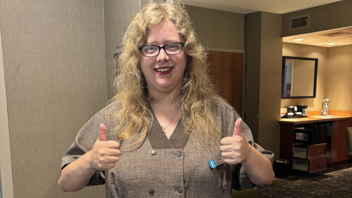 Young woman with disabilities giving a thumbs up at her job
