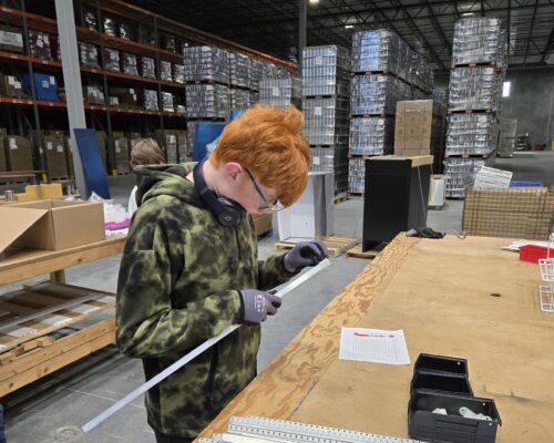 Young male BCI Skills Center Manufacturing student learns to build shelves