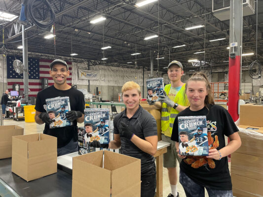Four individuals with disabilities holding cereal boxes they ship from BCI