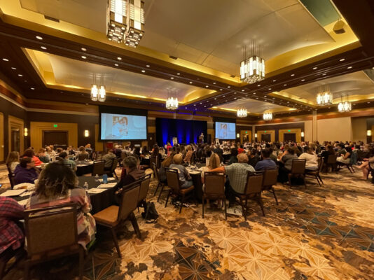 Keynote speaker addresses large ballroom of people