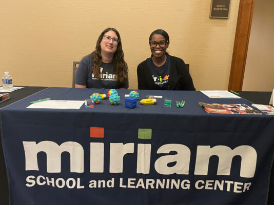 Two women working Miriam School booth