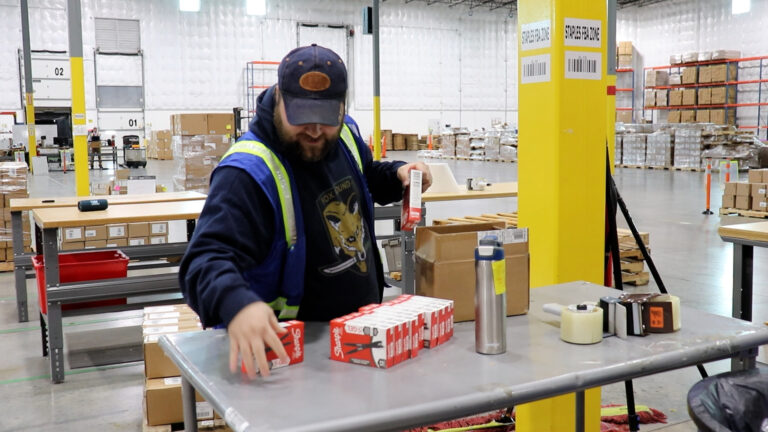 An individual in a warehouse setting works with cardboard boxes, illustrating logistics and warehouse training.