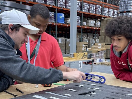 A man working with two students at a workbench