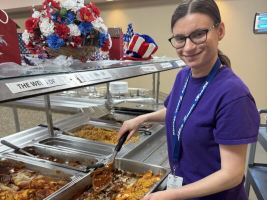 Young woman with a disability putting food on a buffet