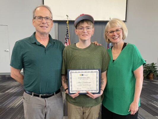 Young man holding a graduation certificate surrounded by his parents