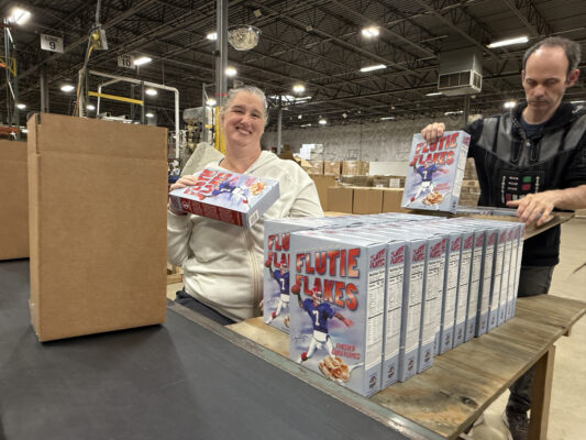 A man and woman with disabilities packaging Flutie Flakes cereal on a production line