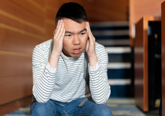 Man with developmental disability looking worried while holding his head